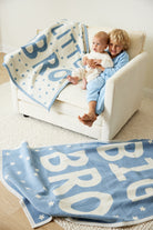 Siblings playing with the Chappywrap Big Bro blanket on a sofa
