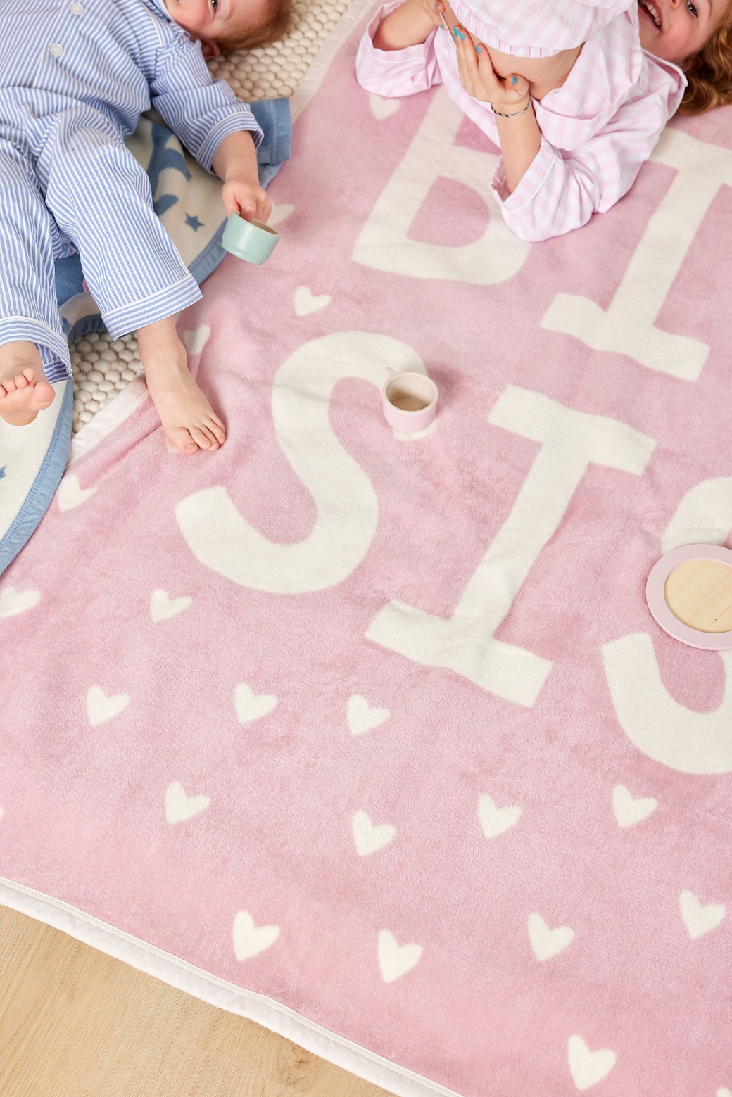 Children playing on the pink Chappywrap Big Sis Midi Blanket with hearts