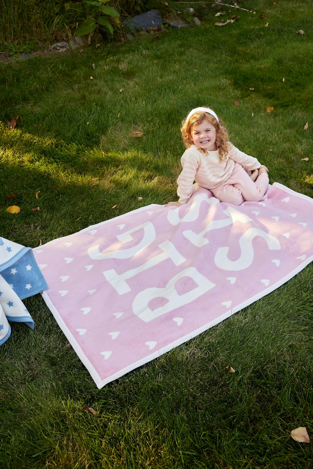 Girl sitting on the Chappywrap Big Sis Midi Blanket on the grass