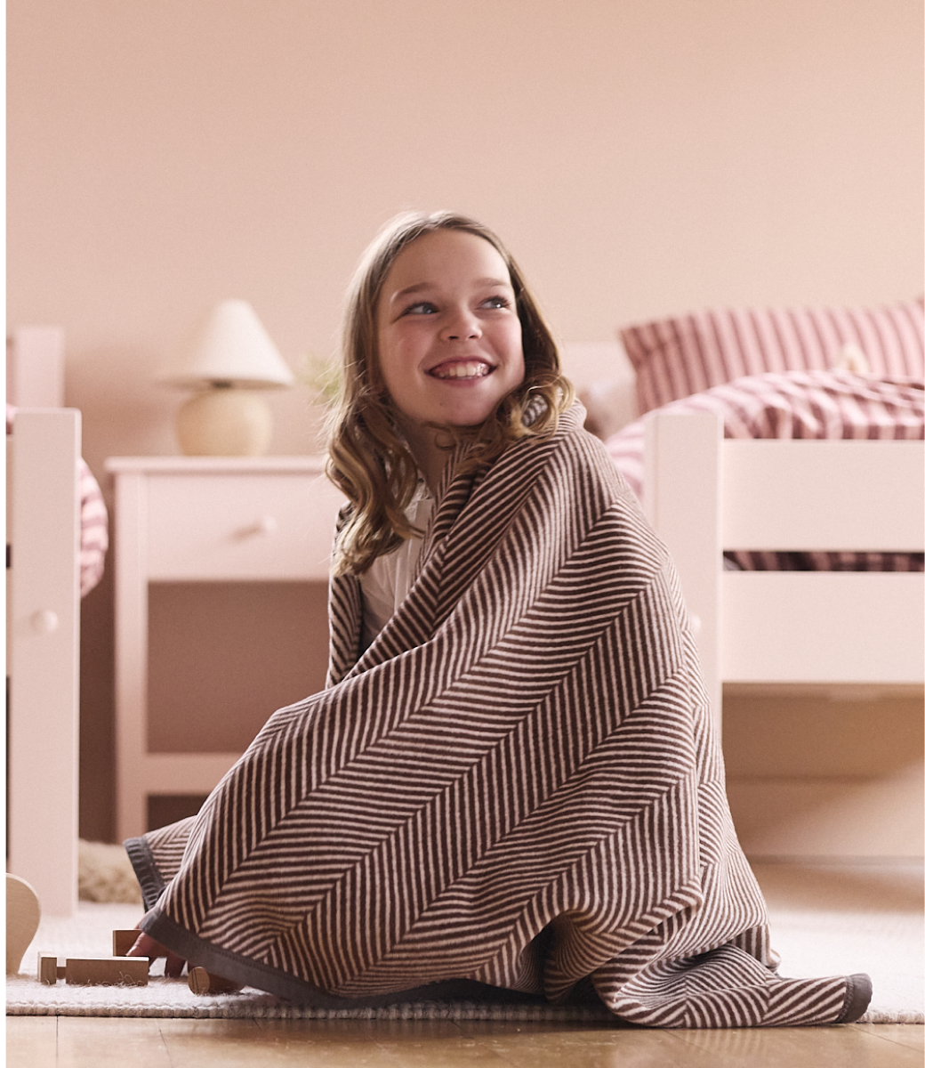 Girl wrapped in the Chappywrap Harborview Herringbone Midi Blanket in Chocolate