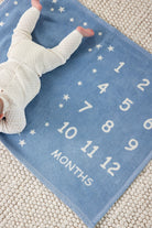 Baby lying on the Chappywrap Milestone Mini Blanket in Fog, a blue month-by-month photo blanket