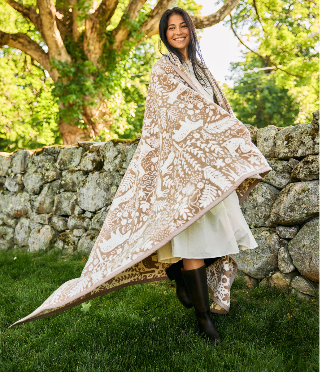 Woman wrapped in the Chappywrap Whimsical Woods Blanket in Sepia, a woodland animal print throw
