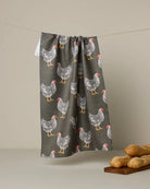 Towel with chicken pattern hanging on a line against a beige background
