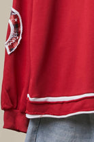 Close-up of the red sweatshirt hem and cuff with white contrast trim