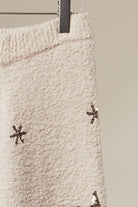 Close-up of the snowflake embroidery on the soft ivory knit sweater pants