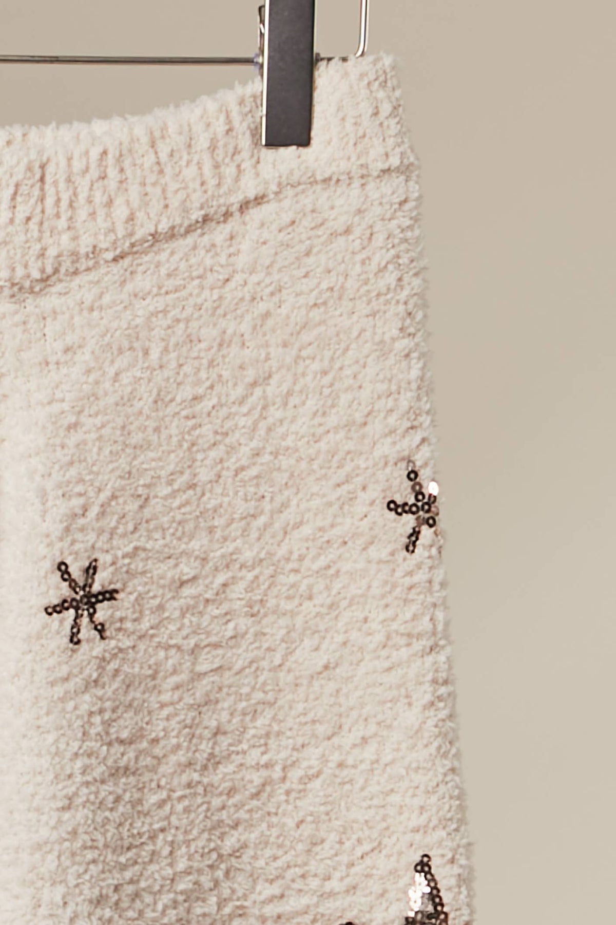 Close-up of the snowflake embroidery on the soft ivory knit sweater pants