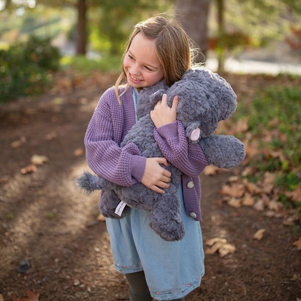 Girl hugging a Chubbees 22 inch weighted plush hippo in soft gray curly fur with pink ears