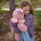 Girl hugging a Chubbees 22 inch weighted plush pig in soft pink curly fur