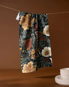 Classic Floral tea towel in deep green with cream, blush, and rust flowers hanging on a line