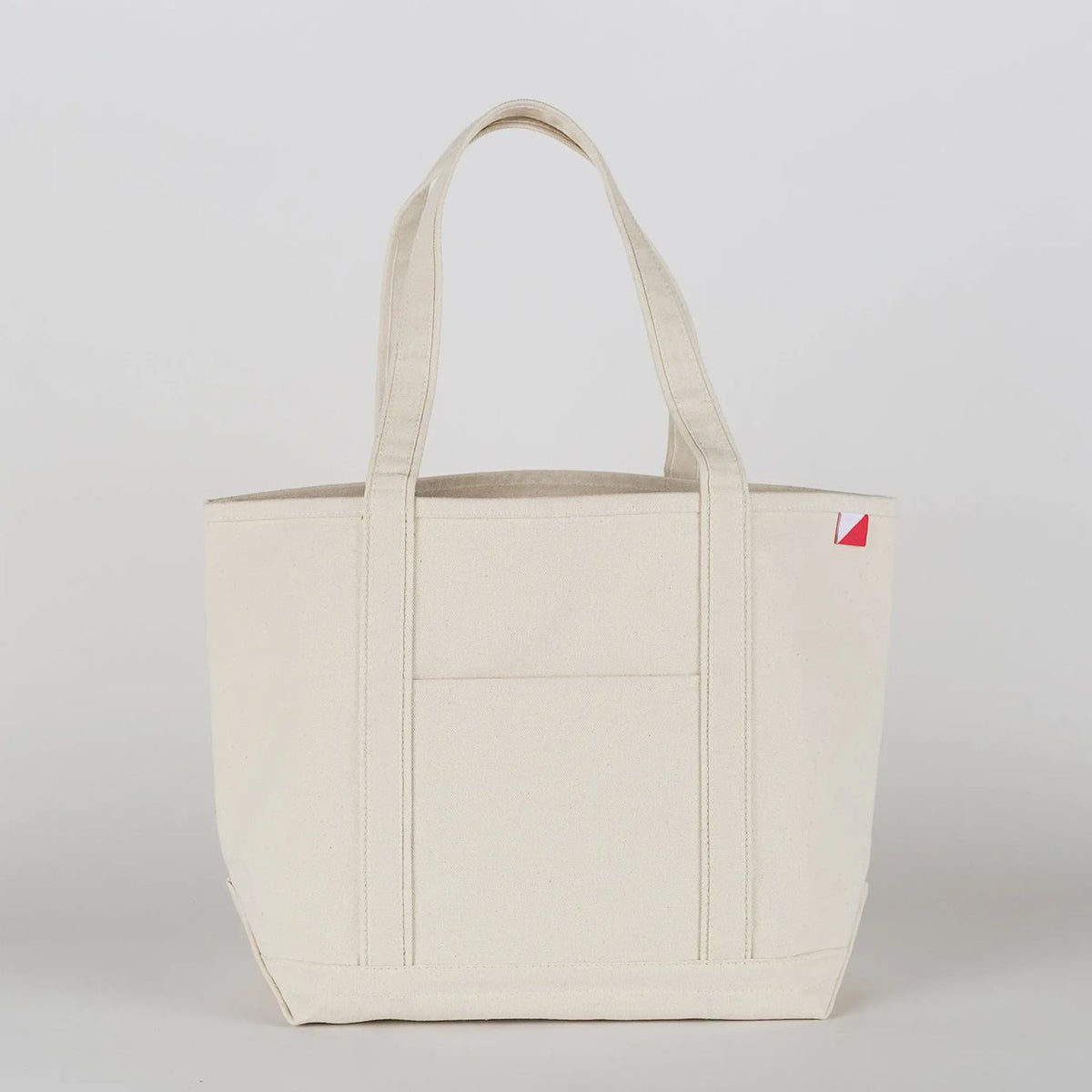 Beige tote bag with a small red logo on a light gray background