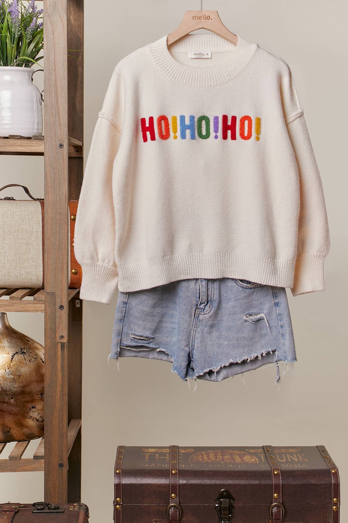 Front of the oversized ivory Colorful Christmas Sweater with multicolor HO HO HO lettering on the chest, styled with denim shorts