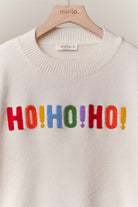 Close-up of the multicolor HO HO HO lettering on the front of the ivory Christmas sweater