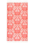 A rectangular woven textile with fringe on both ends, featuring a repeating coral and pink crab pattern on a pale pink background. A small woven label is visible near the lower right edge.