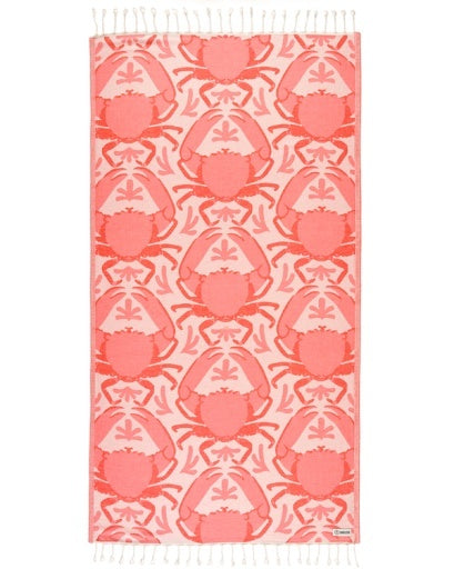 A rectangular woven textile with fringe on both ends, featuring a repeating coral and pink crab pattern on a pale pink background. A small woven label is visible near the lower right edge.