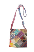 A small crossbody bag with a colorful patchwork print featuring various geometric and floral textile patterns, complete with a tie-dye strap in pink, blue, and purple, shown against a plain white background.