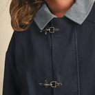 Close-up of the &merci Denim Utility Jacket showing the light-blue corduroy collar and silver clip-clasp closures