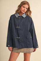 Woman wearing the &merci Denim Utility Jacket in indigo with a light-blue corduroy collar and clip-clasp closures, front view