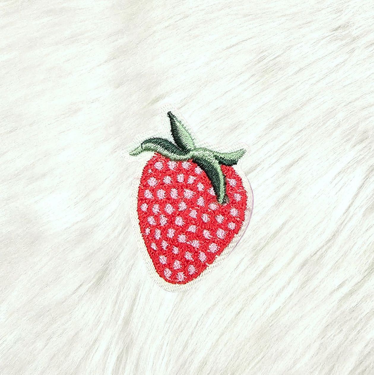 Embroidered strawberry patch on a textured white fabric background