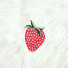 Embroidered strawberry patch on a textured white fabric background