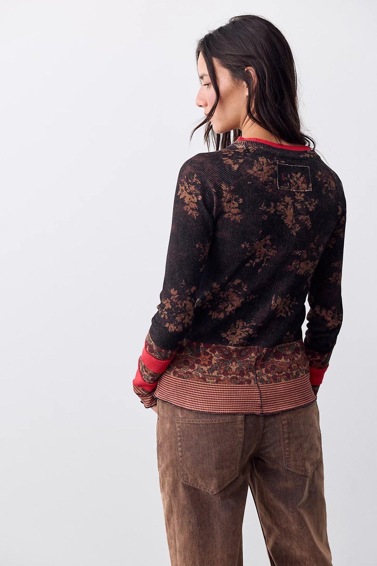 Back view of the Free People Easy Does It Printed Top in black with rust floral print, red neckline trim, and layered-look striped hem