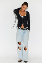 Model wearing the black End Game Pointelle Long Sleeve with distressed light-wash jeans