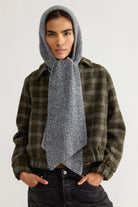 Model wearing the Free People Extra Large Balabonnet in grey, an oversized ribbed knit hood with long scarf ties, over a green plaid jacket