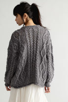Back view of the Free People Opal Cardigan in steel grey, showing the oversized fit, dropped shoulders, and all-over chunky cable knit