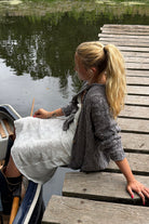 Free People Opal Cable Knit Cardigan in Steel Grey styled outdoors by the water