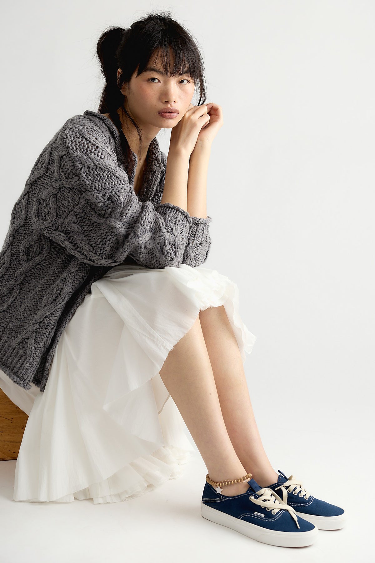 Model seated in the Opal chunky cable knit cardigan in Steel Grey, oversized with dropped shoulders