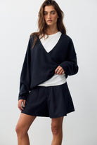 Model wearing the Free People See Me V-Neck Pullover in black with a mini skirt