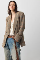 Full-length view of the Free People Shiloh Blazer in brown plaid, worn open over a cream lace top with light wash jeans and a brown belt