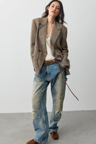 Full-length side view of the Free People Shiloh Blazer in brown plaid over light-wash jeans