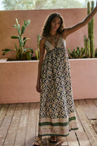 Woman in a patterned dress standing on a wooden deck with cacti in the background