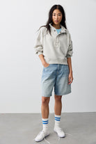 Model wearing the We The Free Timeless Funnel Neck Pullover in Heather Grey with denim shorts and sneakers