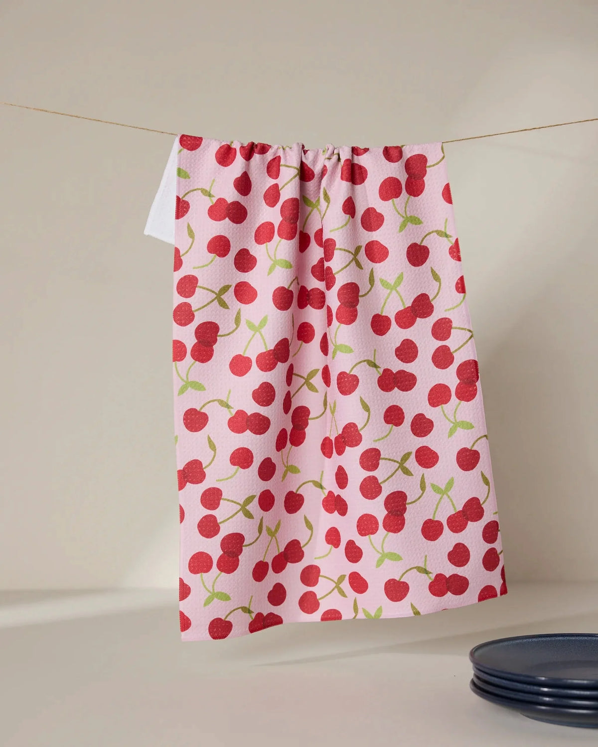 Geometry Cherry Cherries tea towel with red cherries on pink, styled in a kitchen
