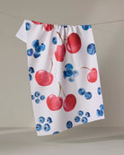 Geometry Cherry On Top tea towel laid flat with a cherry and blueberry print