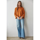 Ginger orange cable-knit cotton pullover sweater with three-quarter sleeves, worn with light wash flare jeans