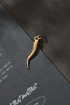 Gold necklace pendant on a black surface with 'it that matters' branding.