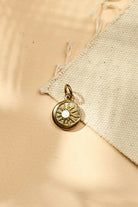 Gold pendant with a sun design on a beige fabric background