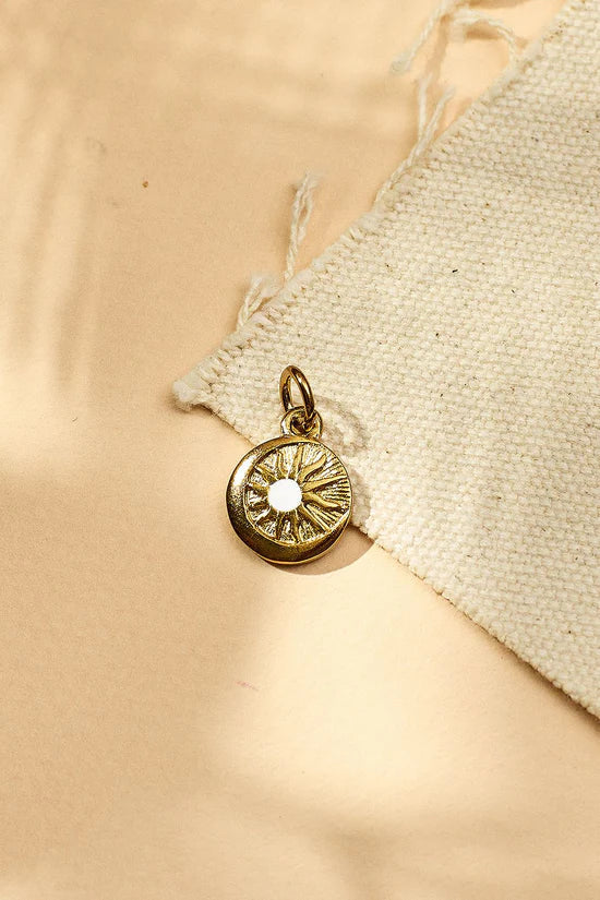 Gold pendant with a sun design on a beige fabric background