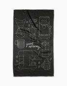 Black towel with white coffee-themed illustrations and 'good morning' text on a white background