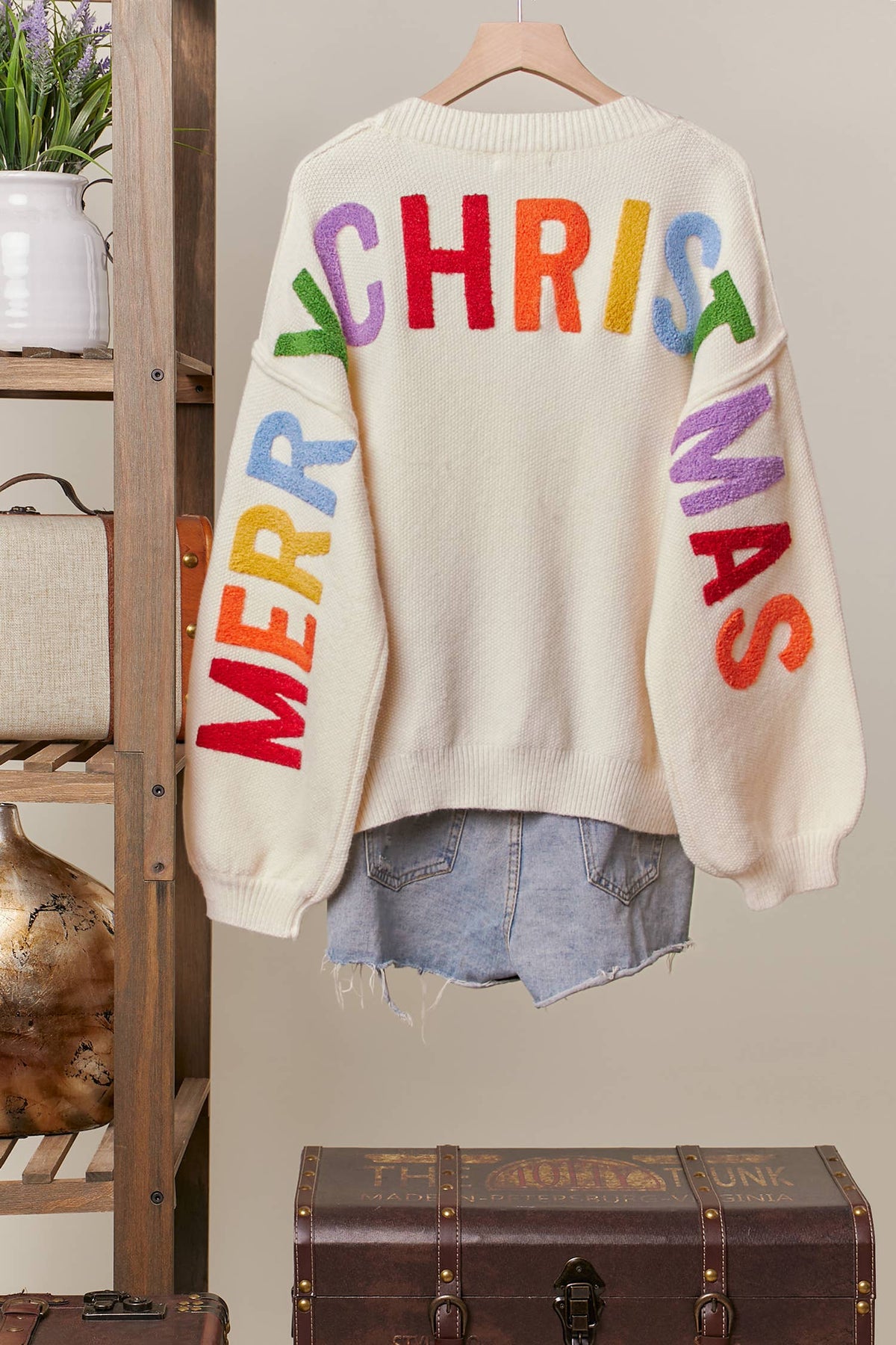 Back of the ivory Ho Ho Ho cardigan with multicolor Merry Christmas lettering across the back and sleeves