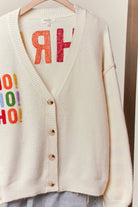 Ivory Ho Ho Ho V-neck cardigan buttoned up showing the button front and ribbed hem