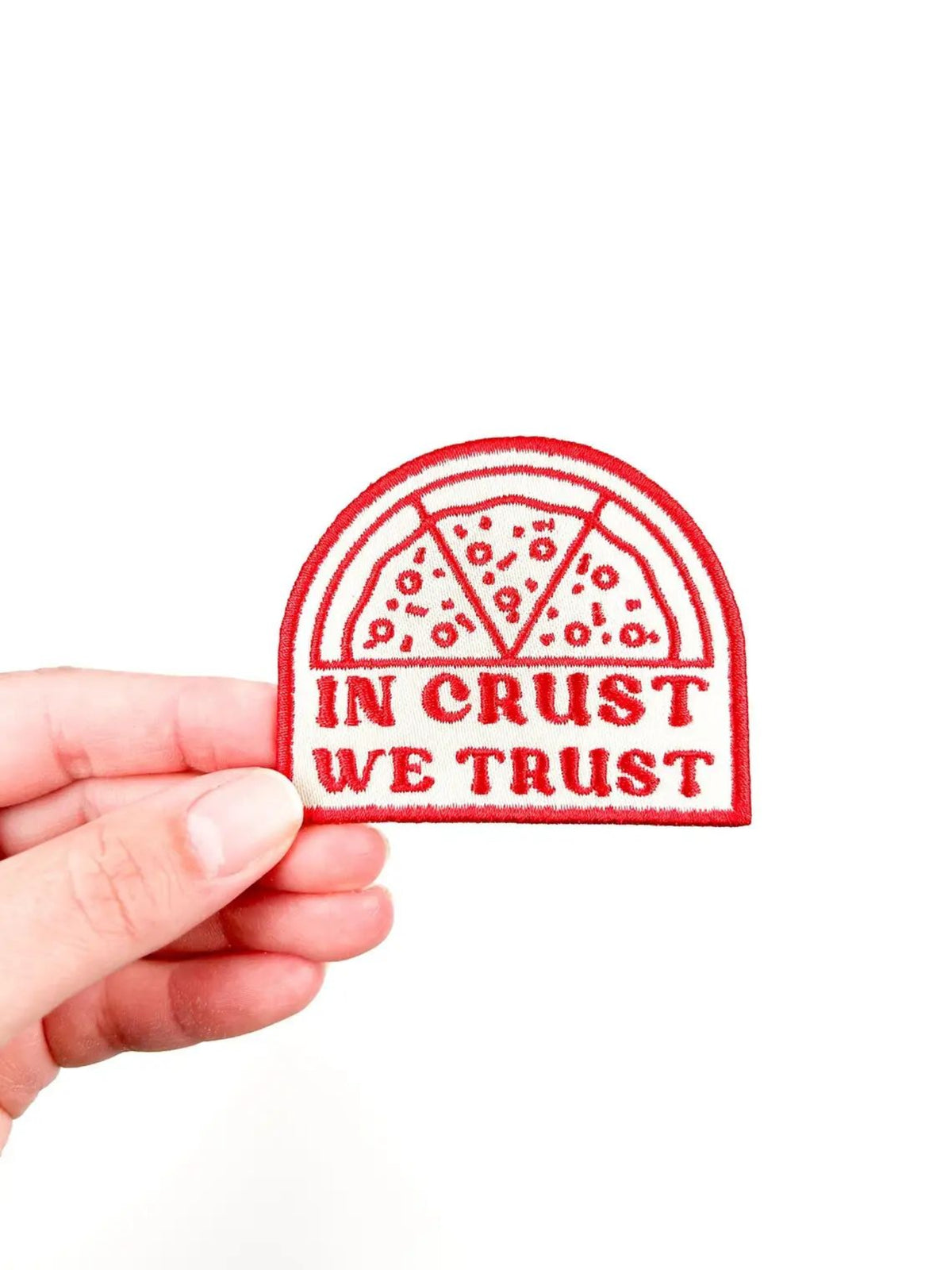 Red pizza-shaped stamp with 'In Crust We Trust' text held by a hand on a white background