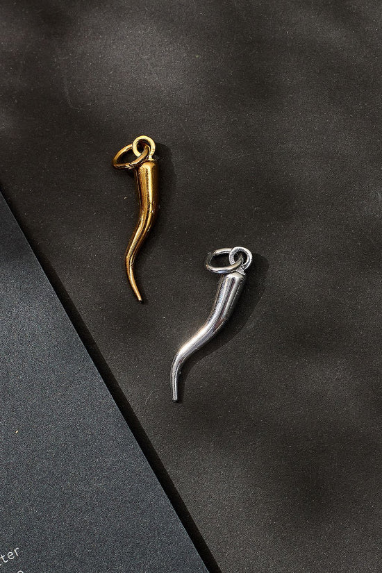 Gold and silver horn-shaped earrings on a dark surface