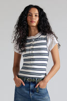 Woman wearing a striped shirt and jeans against a plain background