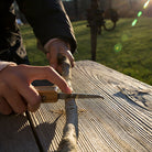 Whittling a stick outdoors with the Kikkerland Huckleberry pocket knife