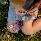 Child making a fresh flower necklace outdoors with the Huckleberry kit