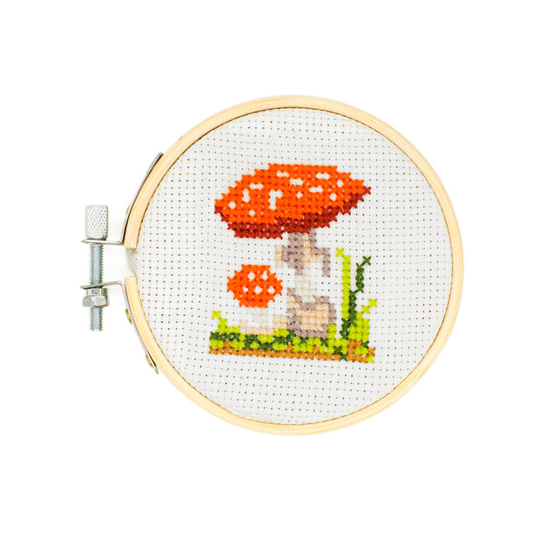 Finished mushroom mini cross stitch in an embroidery hoop from the Kikkerland kit