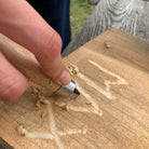 Hands whittling wood with the Kikkerland Huckleberry wood carving tool